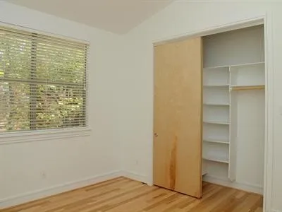 a view of an empty room with a window and wooden floor