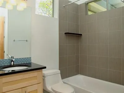 a bathroom with a granite countertop sink a toilet and shower