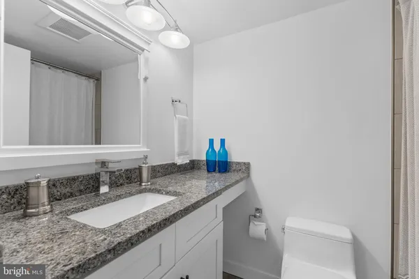 a bathroom with a granite countertop sink and a toilet
