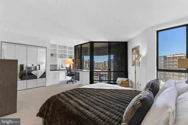 a spacious bedroom with a bed a table and windows