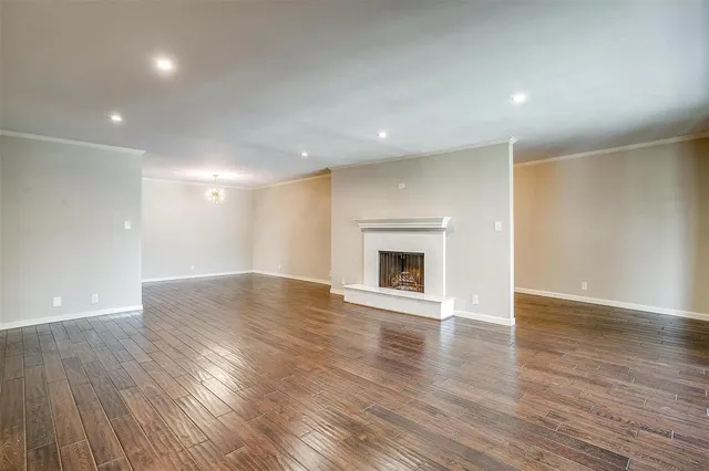 a view of an empty room with wooden floor and a fireplace