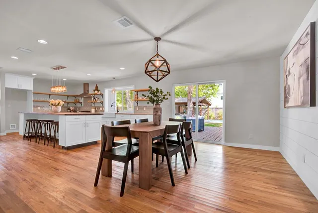 a dining room with wooden floor a chandelier a wooden table and chairs