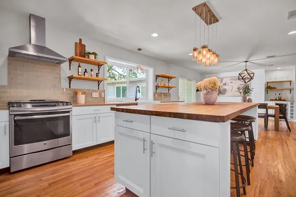 a kitchen with stainless steel appliances granite countertop a stove and a wooden floors