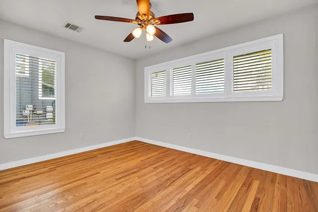 a view of empty room with wooden floor and fan