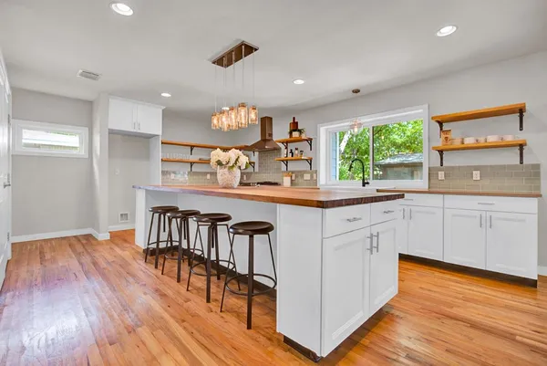 a kitchen with stainless steel appliances granite countertop a stove a sink dishwasher and a dining table with wooden floors