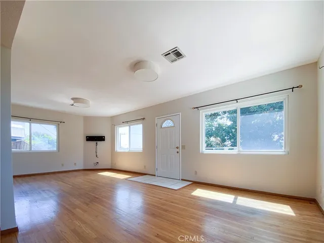 an empty room with wooden floor and windows