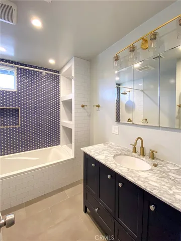 a bathroom with a granite countertop sink mirror and bathtub