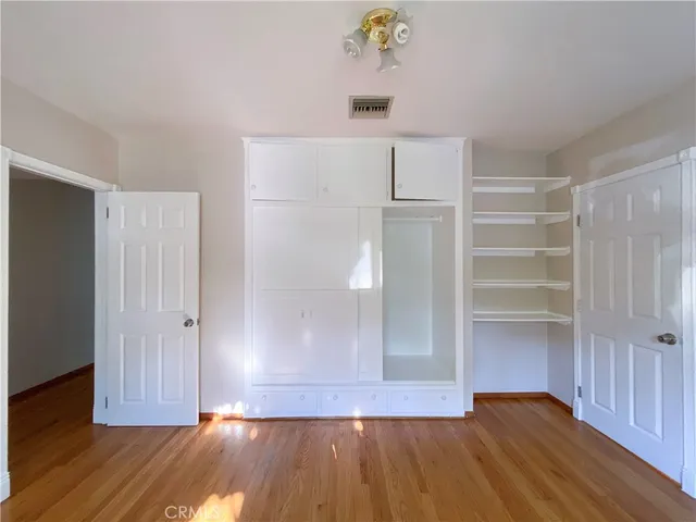 a view of an empty room with wooden floor and closet