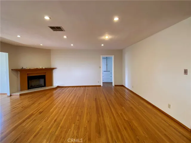 a view of empty room with wooden floor and fireplace