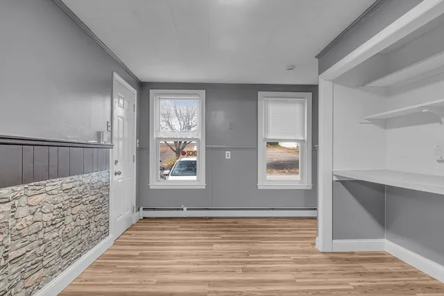 a view of an empty room with wooden floor and window