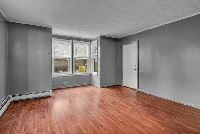 a view of an empty room with window and wooden floor