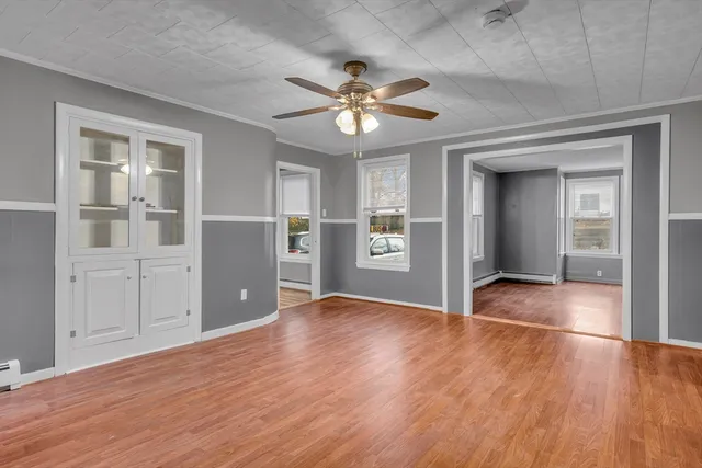 a view of an empty room with window and wooden floor