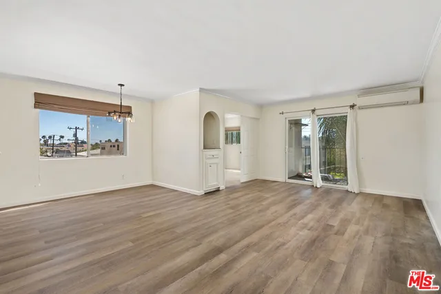 a view of an empty room with window and wooden floor