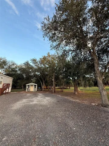a view of dirt field with large trees