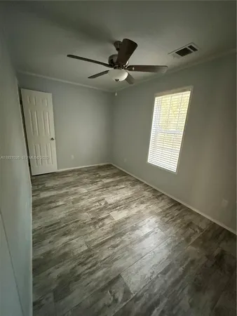 an empty room with windows and fan