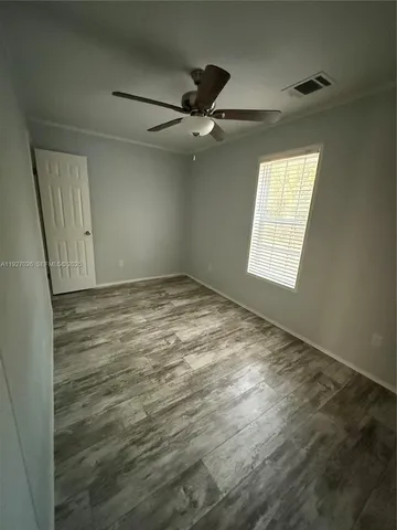 an empty room with windows and fan