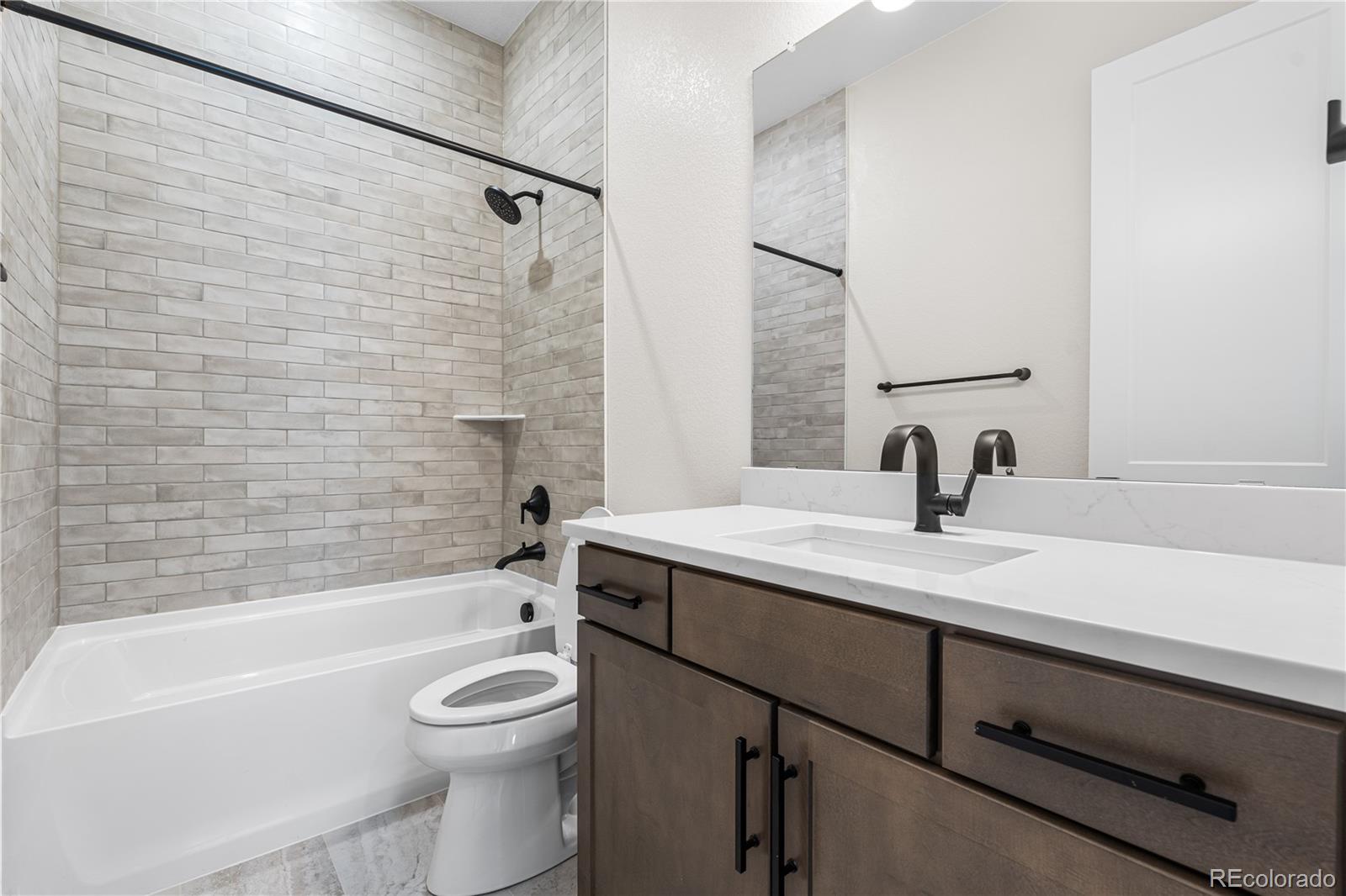 7392 Timberstone Street Castle Pines, CO 80108 - Photo 21 of 42 a bathroom with a granite countertop sink toilet mirror and bathtub