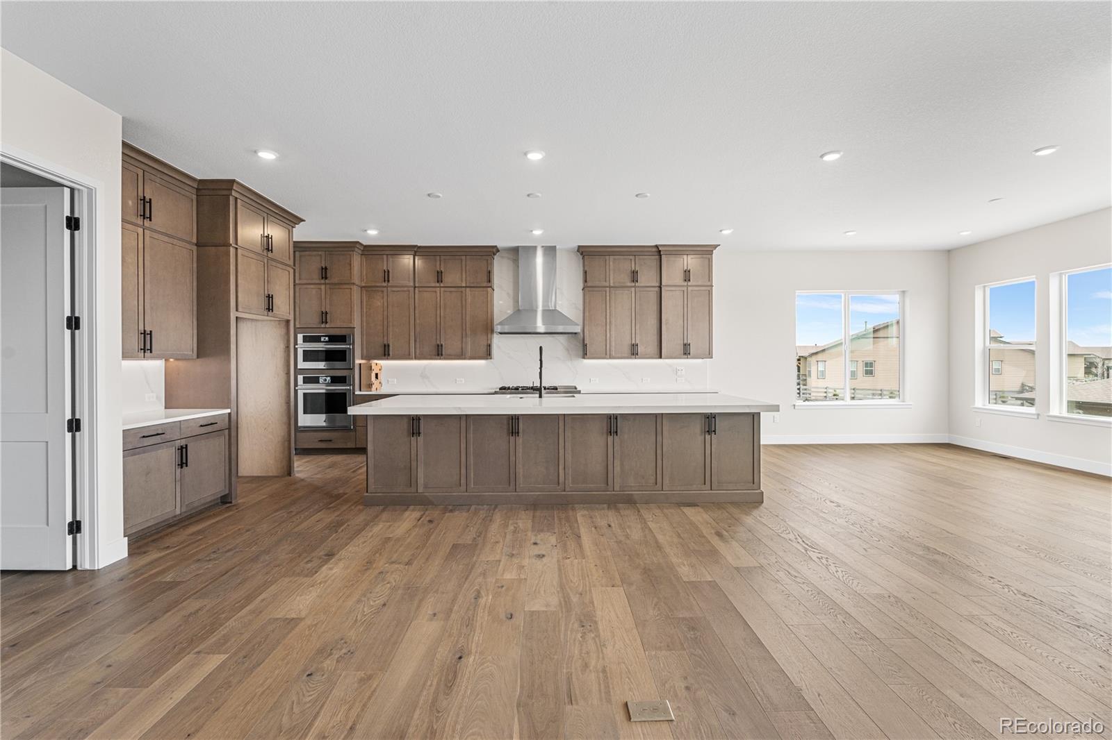 7392 Timberstone Street Castle Pines, CO 80108 - Photo 8 of 42 a large kitchen with a center island wooden floor and stainless steel appliances