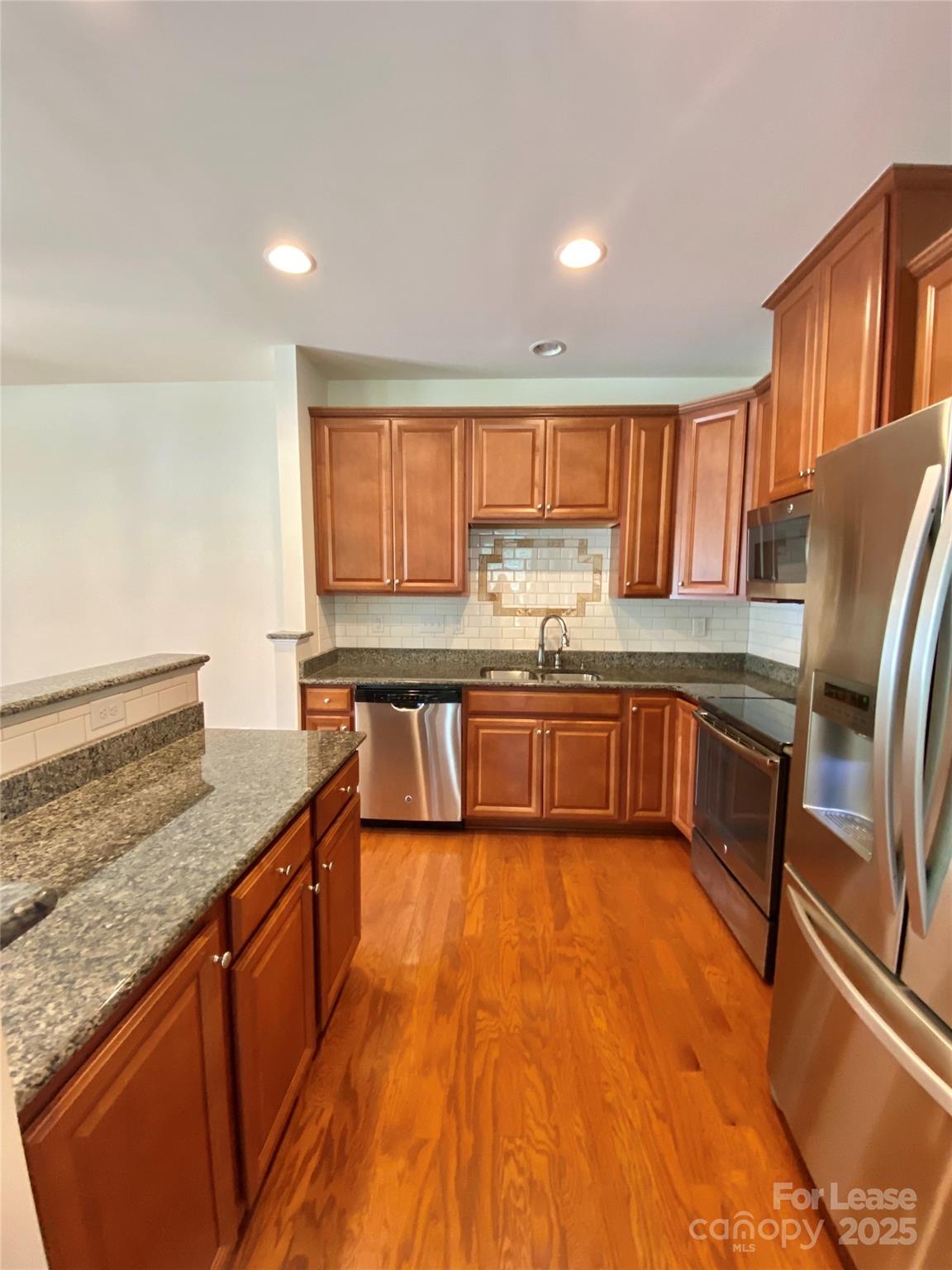 2601 Silverthorn Drive Charlotte, NC 28273 - Photo 13 of 36 a large kitchen with stainless steel appliances granite countertop a stove a sink dishwasher and a microwave oven with wooden floor
