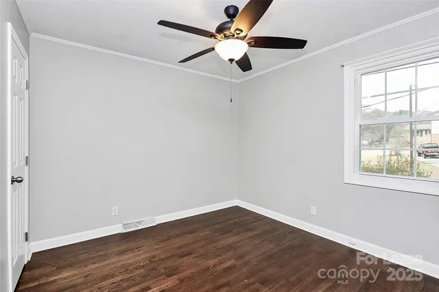an empty room with wooden floor fan and windows