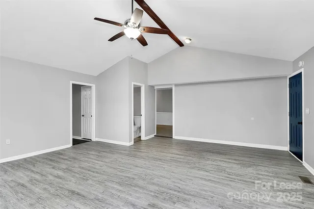 a view of an empty room with wooden floor and a ceiling fan