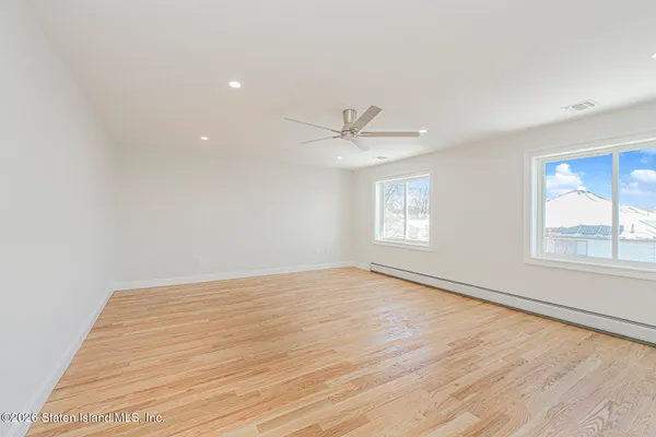 a view of empty room with wooden floor and fan