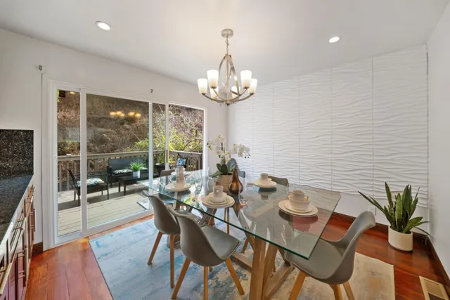 a kitchen with stainless steel appliances granite countertop a stove a sink dishwasher a dining table and chairs with wooden floor