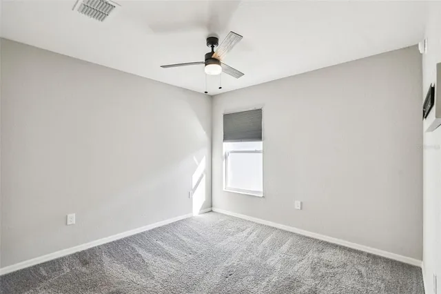 an empty room with a window and a ceiling fan