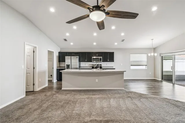 a view of living room with kitchen island stainless steel appliances wooden floor and a window