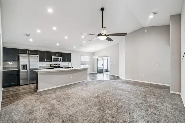 a large kitchen with a large counter top a sink stainless steel appliances and cabinets