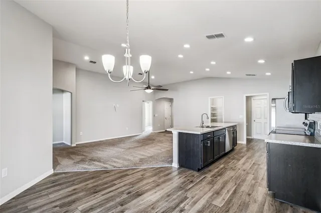a kitchen with stainless steel appliances granite countertop a sink a stove and a wooden floors