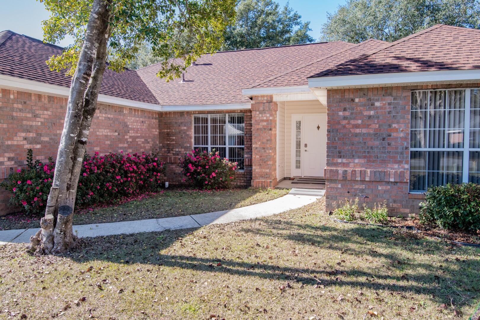 607 Risen Star Drive Crestview, FL 32539 - Photo 3 of 35 a view of a house with a small yard and a large tree