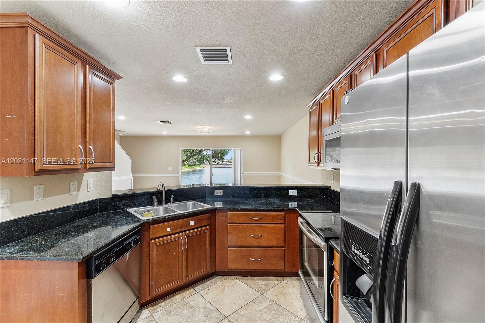 5930 Abbey Road Tamarac, FL 33321 - Photo 6 of 26 a kitchen with granite countertop stainless steel appliances a sink counter space cabinets and a counter top space