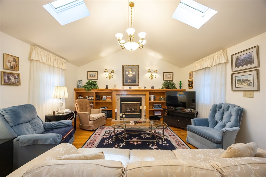 21 Trinity Drive Milford, MA 01757 - Photo 7 of 38 a living room with furniture a fireplace and a chandelier