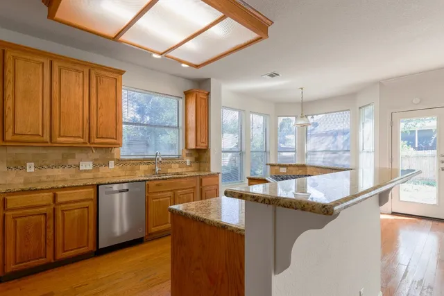 a large kitchen with granite countertop a sink window and cabinets