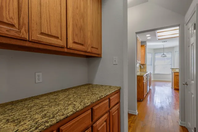 a kitchen with granite countertop wooden cabinets and a wooden floor