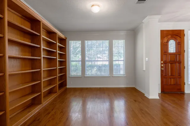 a view of an empty room with a window and wooden floor