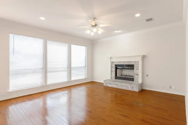 wooden floor fireplace and windows in an empty room