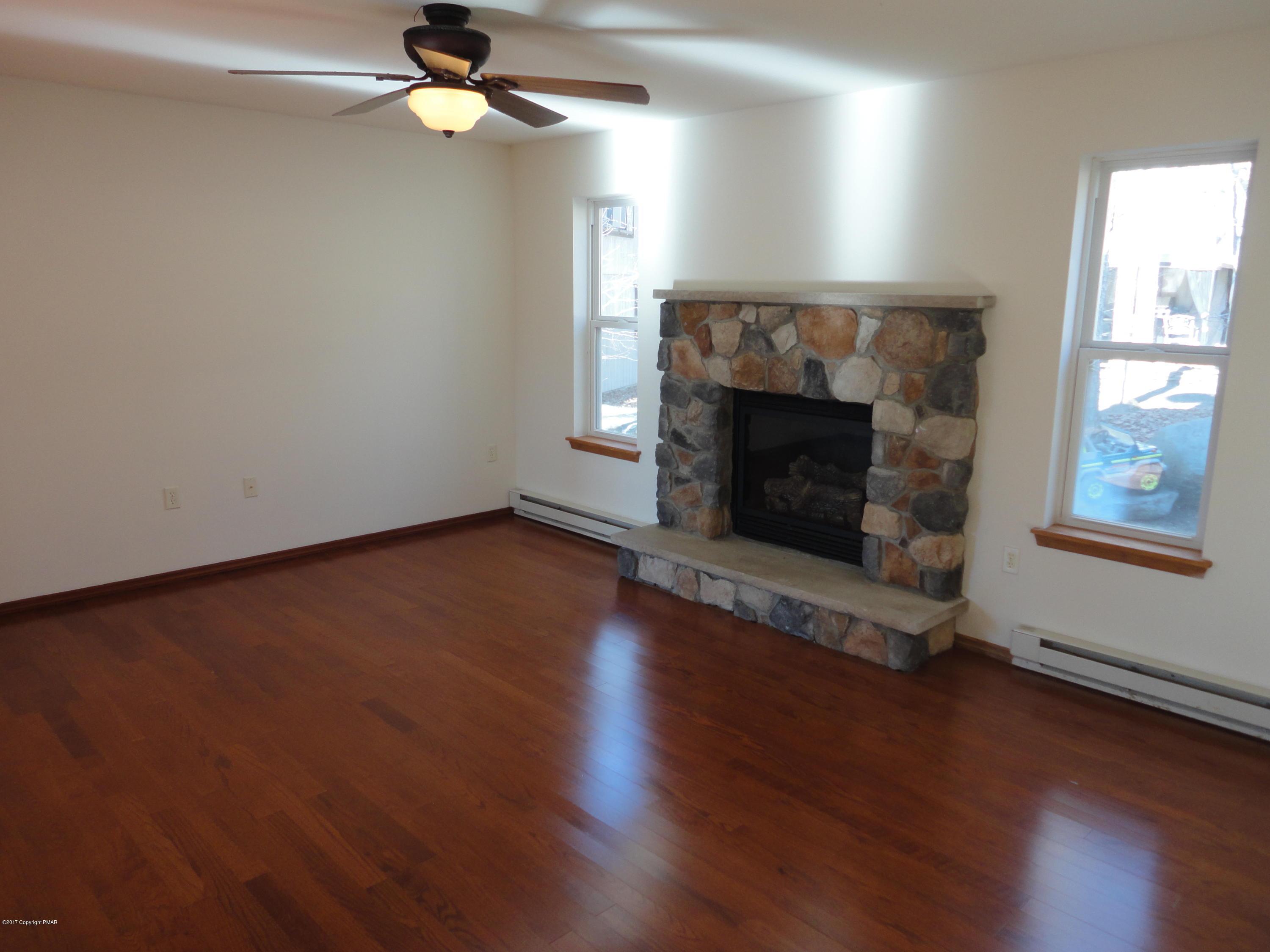 6389 Decker Road Bushkill, PA 18324 - Photo 3 of 22 an empty room with wooden floor fireplace and window
