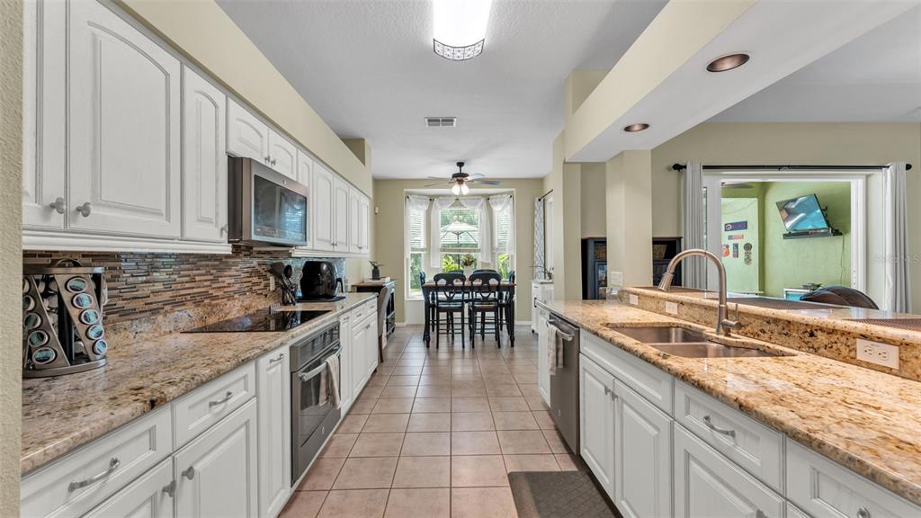 2803 Spring Meadow Drive Plant City, FL 33566 - Photo 16 of 74 a large kitchen with granite countertop a large island in the center and stainless steel appliances