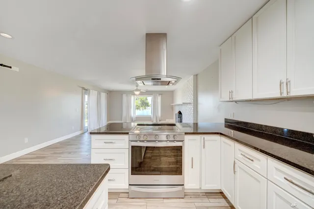 a kitchen with stainless steel appliances white cabinets and wooden floor