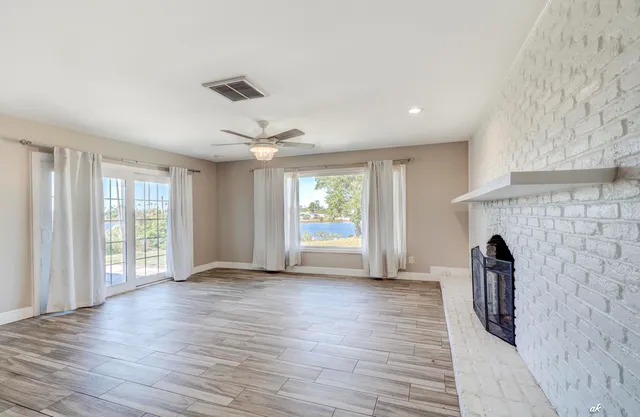 a view of an empty room with a window and wooden floor
