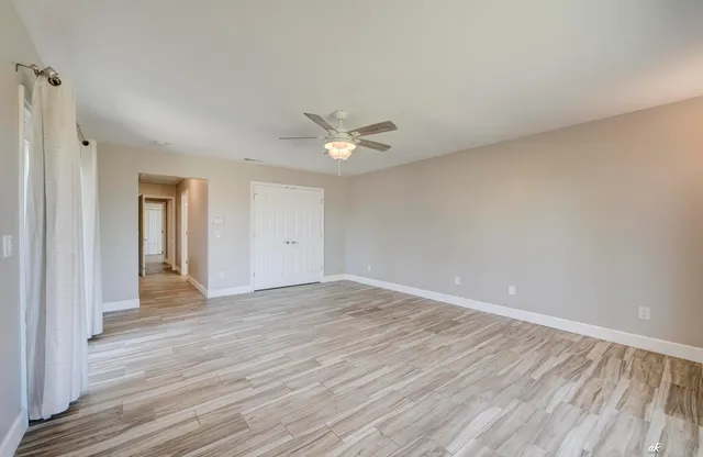 a view of an empty room with wooden floor and a window