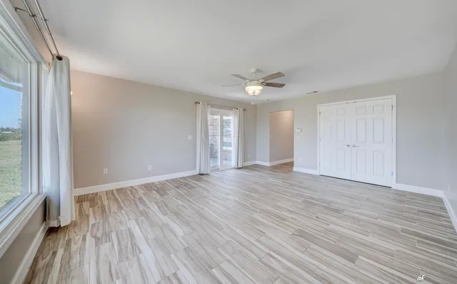 a view of a hallway with wooden floor and a bathroom