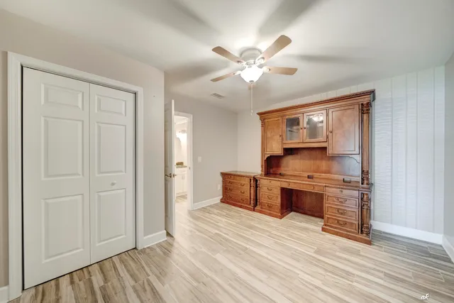 an empty room with wooden floor fan and windows