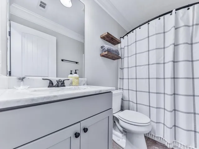 a bathroom with a granite countertop sink a toilet and shower