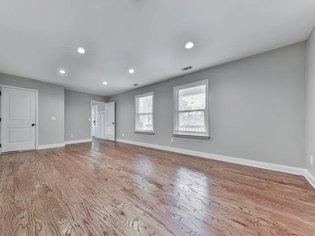 a view of empty room with wooden floor and window