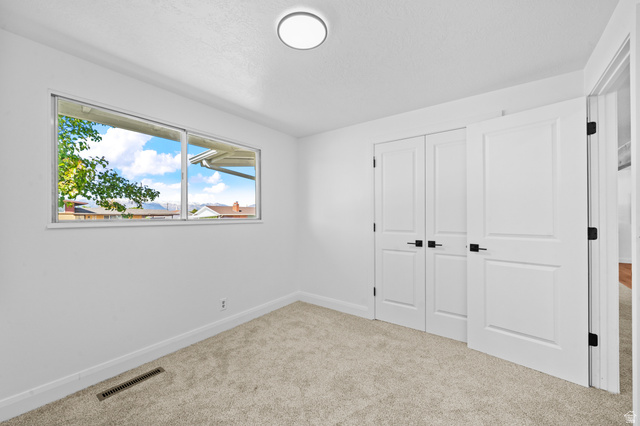2267 West 4350th Street South Roy, UT 84067 - Photo 17 of 32 Unfurnished bedroom featuring a closet, light colored carpet, and a textured ceiling