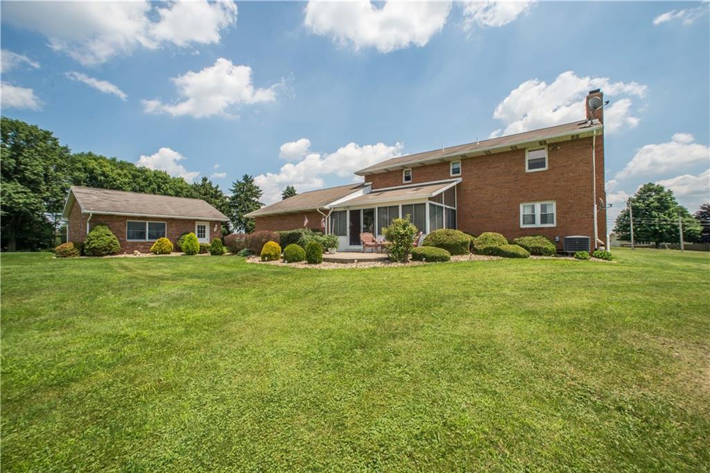 662 Bocktown Cork Road Clinton, PA 15026 - Photo 21 of 25 The rear exterior view highlights the depth of the detached garage and the overall size of the sunroom. Landscaping surrounds the rear patio and matches the plantings found along the front of the home.