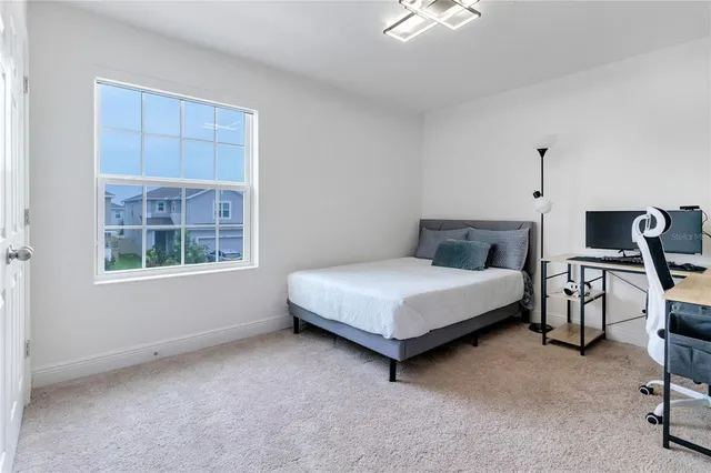 a bedroom with a bed a chair and next to a window